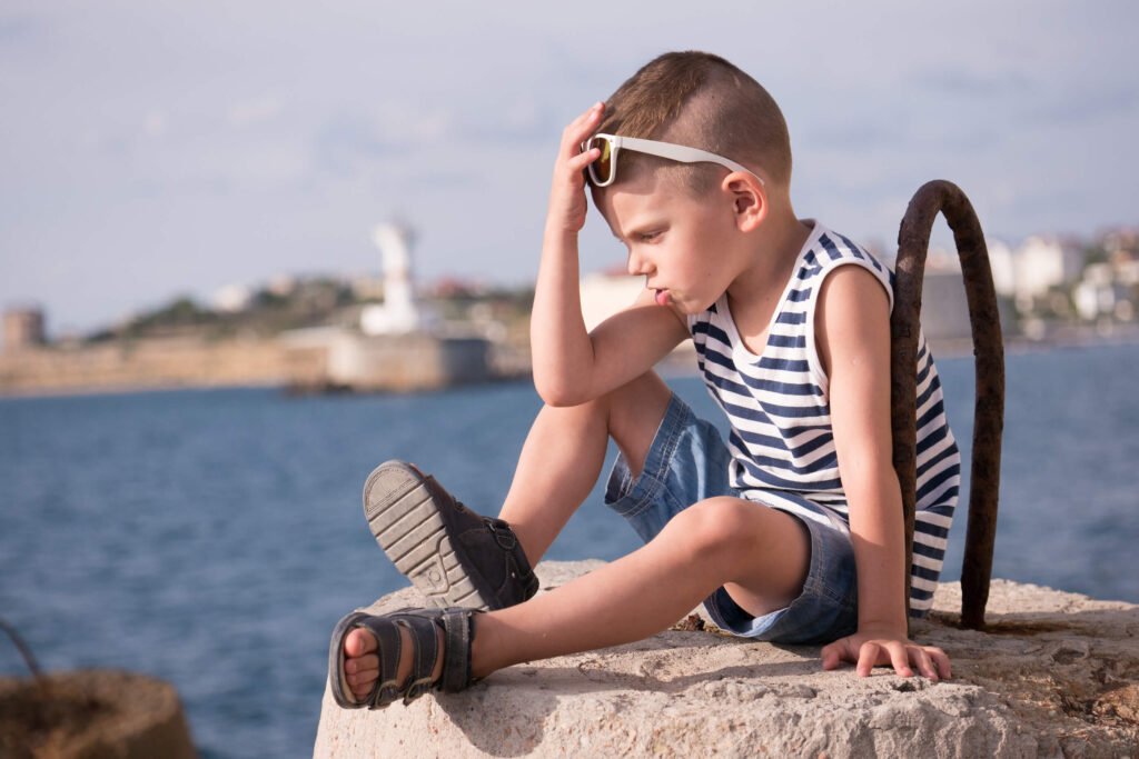 Little boy having a timeout on a dock at a lake.
