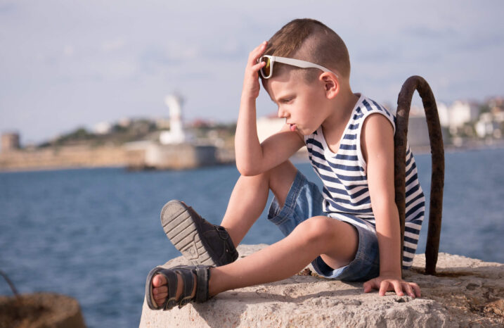 Little boy having a timeout on a dock at a lake.