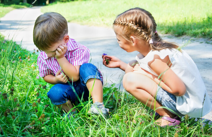 Little girl offering a flower to an upset boy.