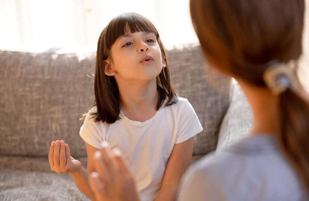 Little girl talking and holding up her hand.