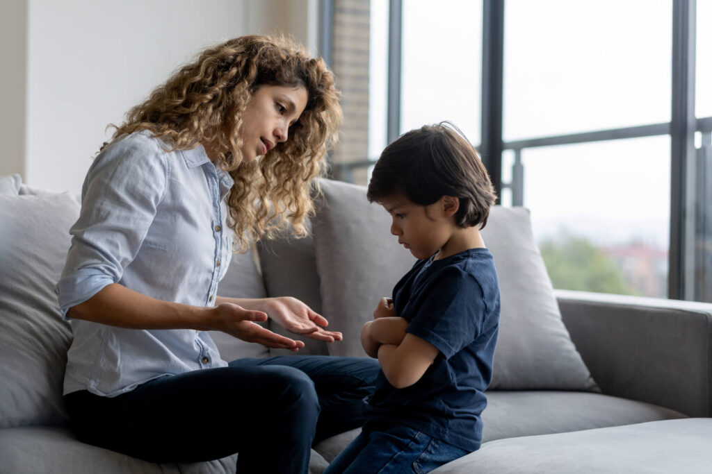 Mom sitting on couch reasoning with her son.