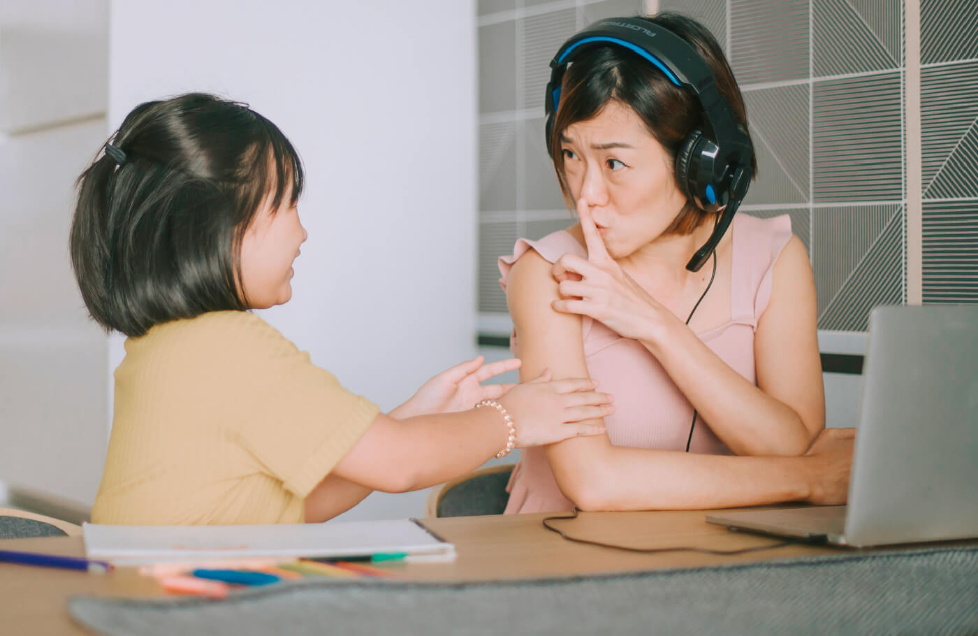 Woman on computer shushing interrupting child.