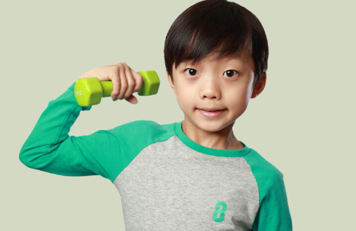 Young boy doing a bicep curl with a weight.