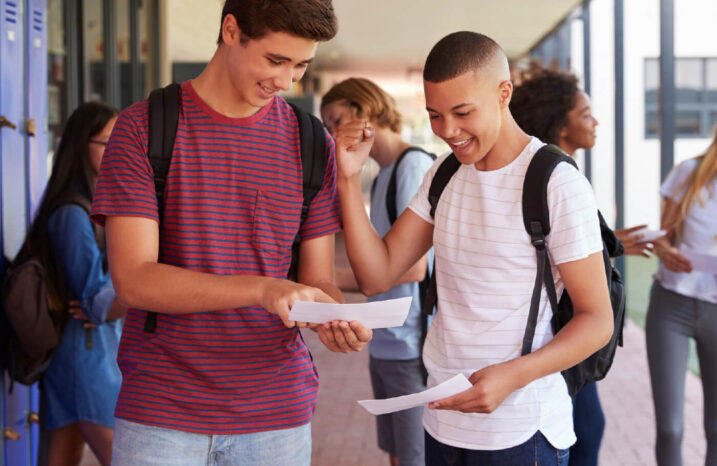 Two teens are looking excitedly at a paper one of them is holding.