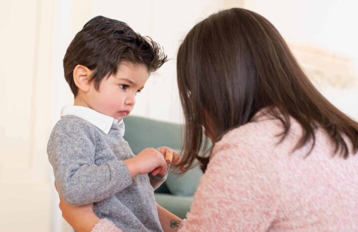 Woman with her back to the camera talking to a young boy.